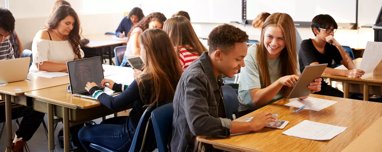 Junge Menschen sitzen an Tischen in einem Klassenzimmer
